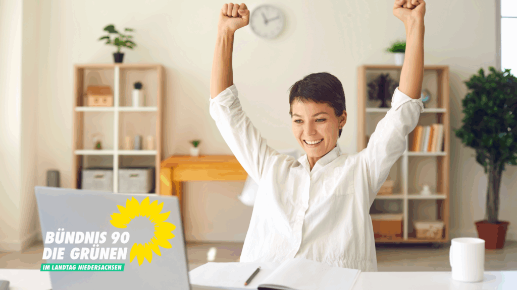 Eine Frau sitzt vor einem aufgeklappten Laptop am Schreibtisch und hat ihre Arme zum Jubeln hochgehoben.